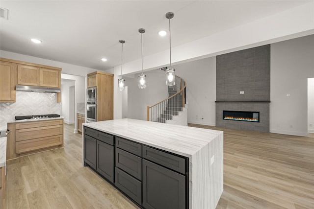 kitchen featuring hanging light fixtures, light wood-type flooring, light brown cabinets, gas cooktop, and a kitchen island