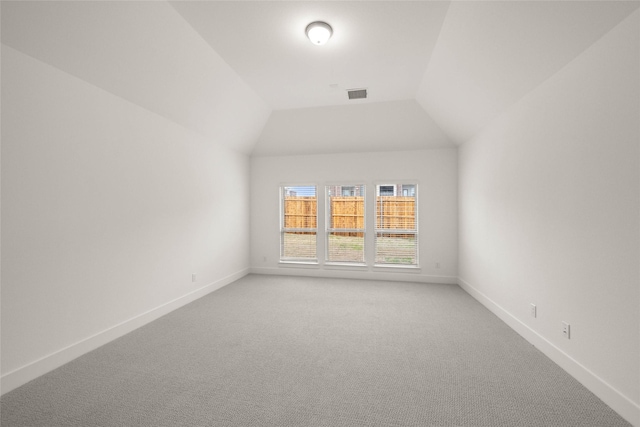 carpeted spare room featuring vaulted ceiling