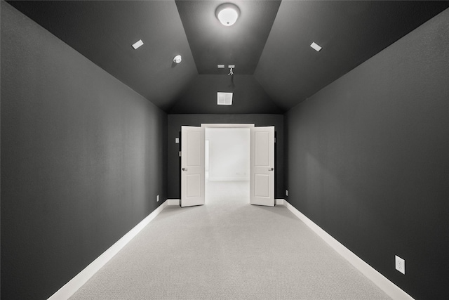 unfurnished room featuring lofted ceiling and light colored carpet