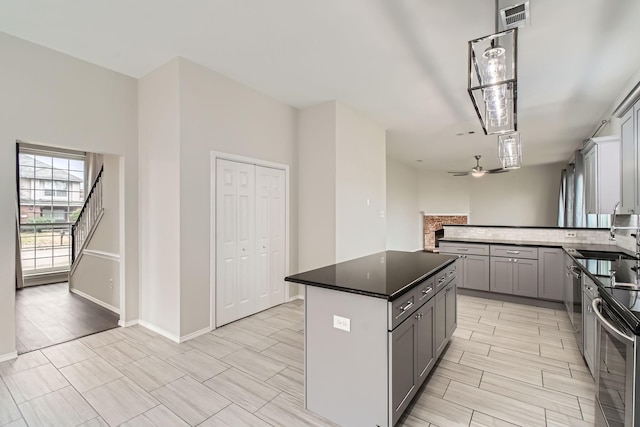 kitchen featuring gray cabinets, sink, a center island, ceiling fan, and stainless steel appliances