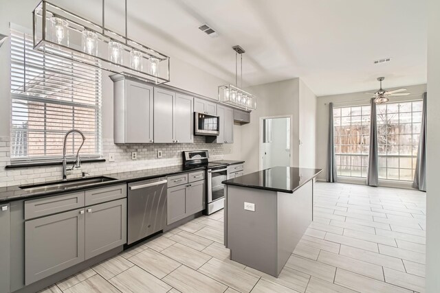 kitchen featuring hanging light fixtures, gray cabinets, a center island, and stainless steel appliances