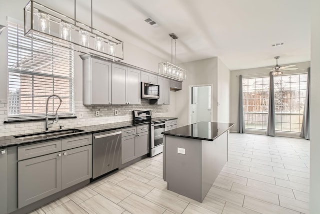 kitchen with appliances with stainless steel finishes, gray cabinets, sink, and a kitchen island