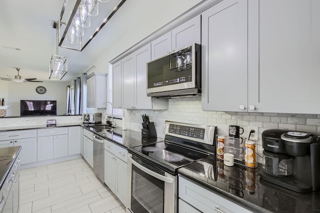 kitchen with appliances with stainless steel finishes, backsplash, dark stone counters, ceiling fan, and sink