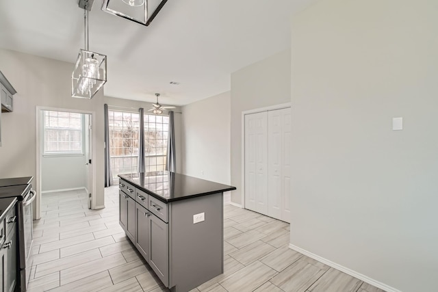 kitchen with gray cabinetry, stainless steel range with electric stovetop, a center island, hanging light fixtures, and ceiling fan