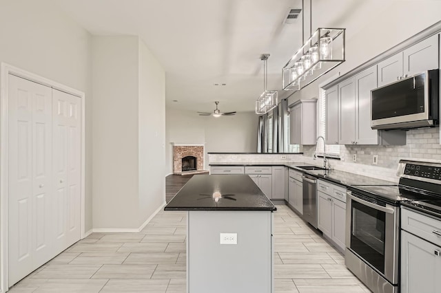 kitchen featuring gray cabinetry, sink, stainless steel appliances, and a center island