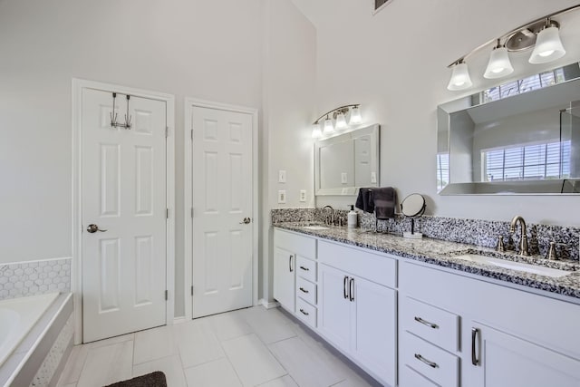 bathroom with tile patterned flooring, a towering ceiling, vanity, and tiled bath