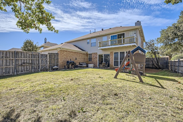 rear view of house featuring a lawn, a balcony, and a playground