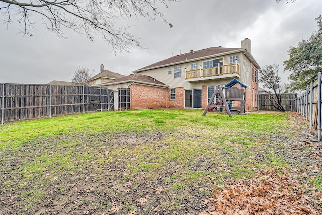 back of house featuring a balcony and a yard