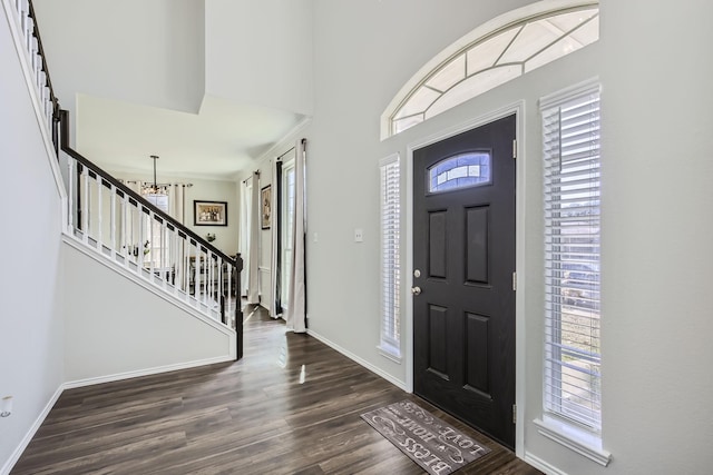 entryway with a barn door, an inviting chandelier, dark wood-type flooring, and ornamental molding