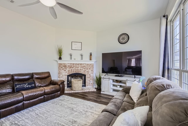 living room with dark hardwood / wood-style floors, a brick fireplace, and ceiling fan