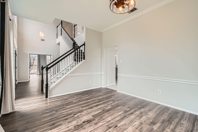 interior space featuring crown molding, dark wood-type flooring, and a high ceiling