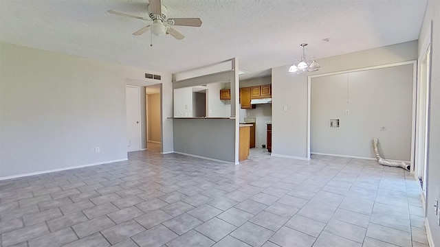 unfurnished living room featuring ceiling fan with notable chandelier and a textured ceiling