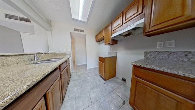 kitchen featuring light stone counters, sink, and a textured ceiling