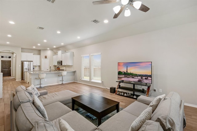 living room with ceiling fan, light hardwood / wood-style flooring, and sink