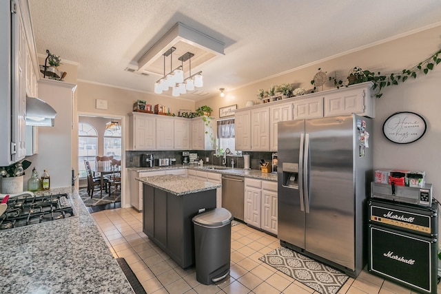 kitchen featuring appliances with stainless steel finishes, light stone counters, sink, a center island, and light tile patterned flooring