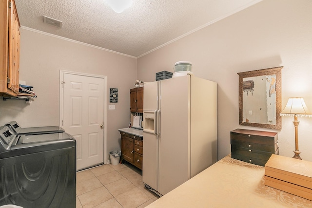 washroom with ornamental molding, light tile patterned floors, a textured ceiling, and washing machine and clothes dryer