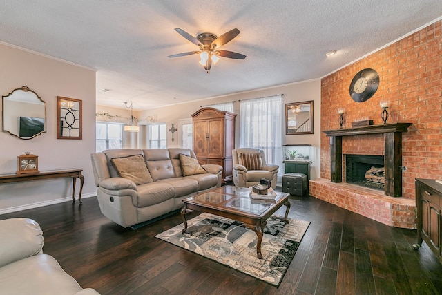 living room featuring ceiling fan, dark wood-type flooring, a brick fireplace, crown molding, and a textured ceiling