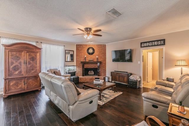 living room featuring ceiling fan, dark wood-type flooring, a textured ceiling, and a brick fireplace