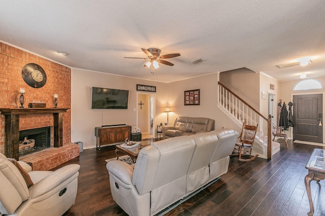 living room featuring ornamental molding, a brick fireplace, dark hardwood / wood-style floors, and a textured ceiling