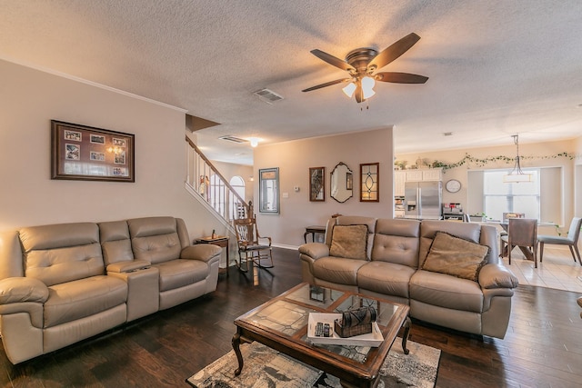 living room featuring ceiling fan, dark wood-type flooring, and a textured ceiling