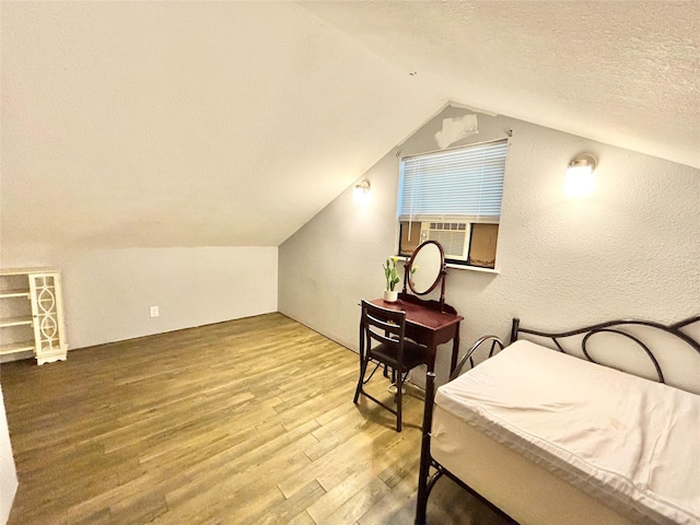 bedroom featuring hardwood / wood-style floors, cooling unit, a textured ceiling, and vaulted ceiling