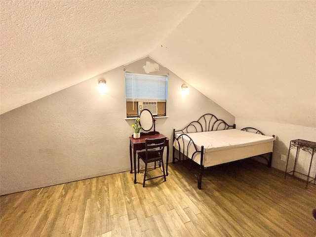 bedroom with lofted ceiling, cooling unit, a textured ceiling, and light wood-type flooring