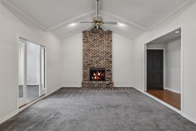 unfurnished living room featuring lofted ceiling, dark colored carpet, crown molding, a brick fireplace, and ceiling fan