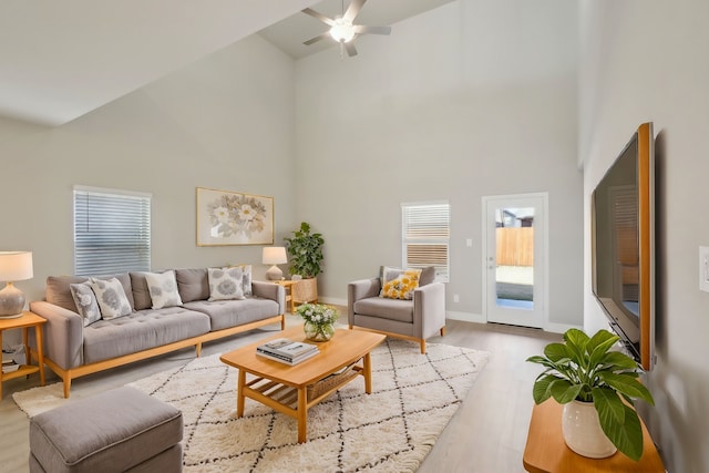 living room with ceiling fan, light hardwood / wood-style flooring, and high vaulted ceiling