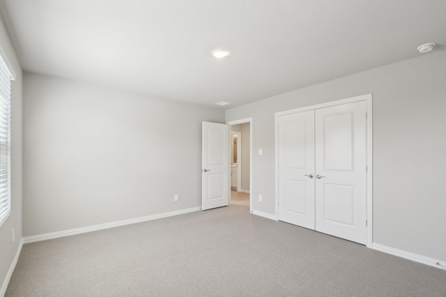 unfurnished bedroom with light carpet and a closet