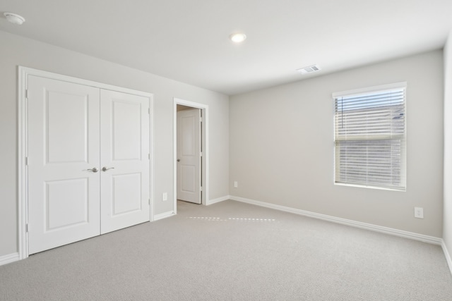 unfurnished bedroom with light carpet and a closet