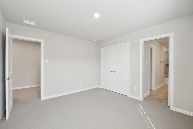 unfurnished bedroom featuring light colored carpet and a closet