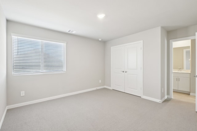 unfurnished bedroom featuring light colored carpet, a closet, and connected bathroom