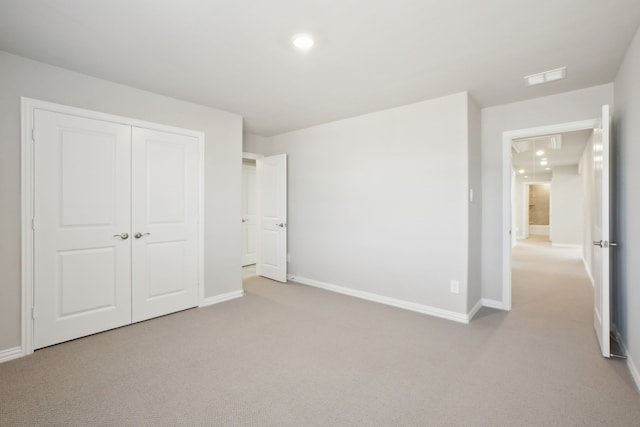 unfurnished bedroom featuring light colored carpet and a closet