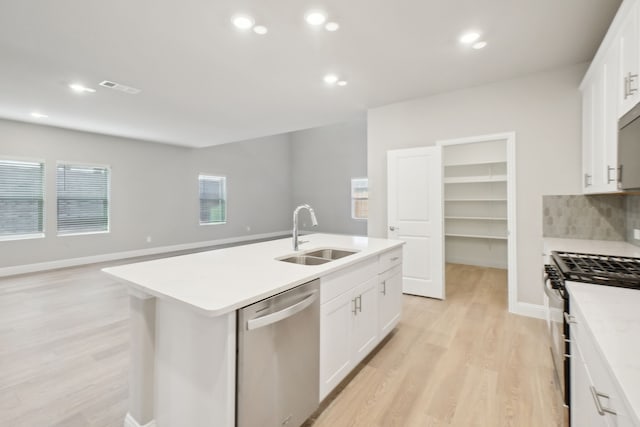 kitchen featuring stainless steel appliances, an island with sink, white cabinetry, and sink