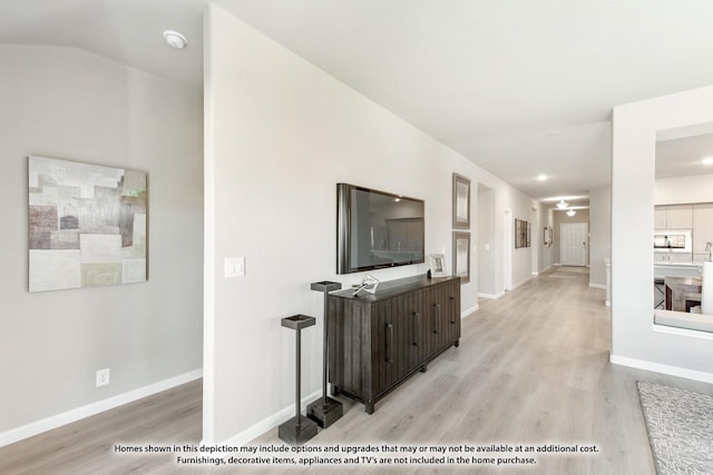 hall with light hardwood / wood-style flooring and lofted ceiling