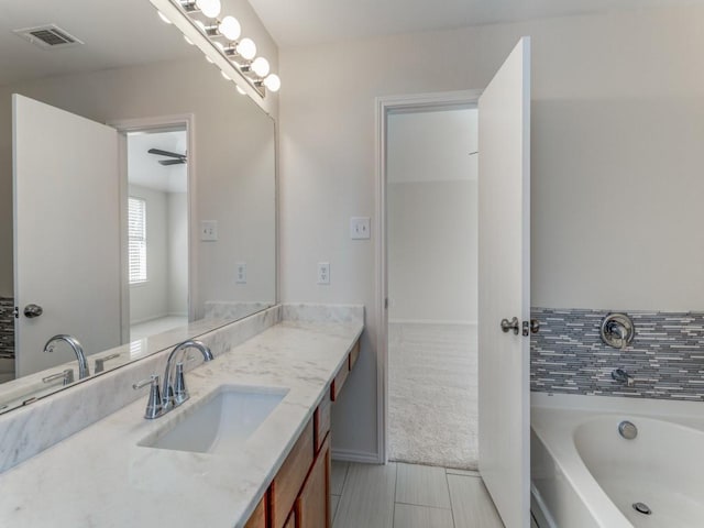 bathroom with ceiling fan, a bathtub, and vanity