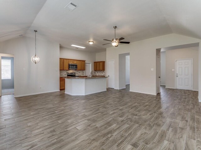 kitchen with appliances with stainless steel finishes, tasteful backsplash, light hardwood / wood-style floors, hanging light fixtures, and lofted ceiling