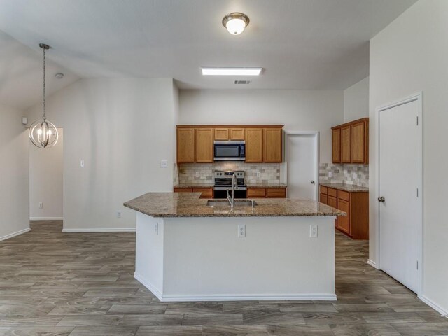 kitchen with pendant lighting, a center island with sink, decorative backsplash, a notable chandelier, and stainless steel appliances