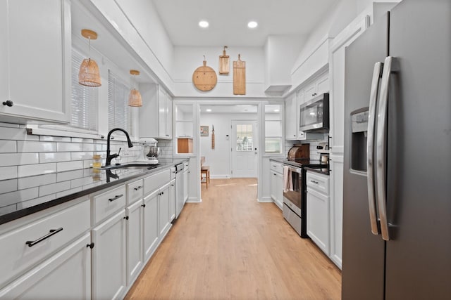 kitchen with appliances with stainless steel finishes, tasteful backsplash, sink, pendant lighting, and white cabinets