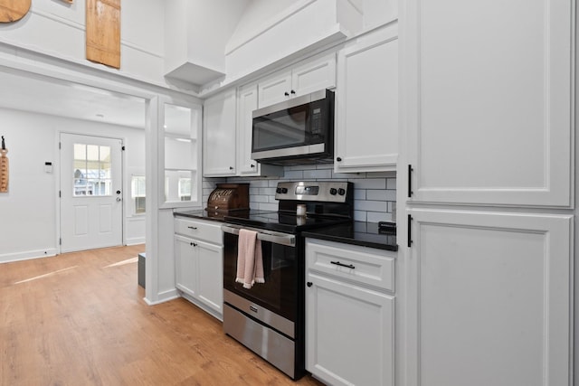 kitchen with white cabinets, light wood-type flooring, backsplash, and appliances with stainless steel finishes