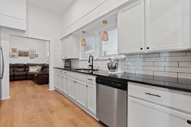 kitchen with pendant lighting, backsplash, sink, stainless steel dishwasher, and white cabinetry