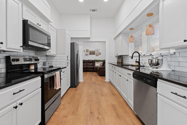 kitchen featuring backsplash, sink, hanging light fixtures, appliances with stainless steel finishes, and white cabinetry