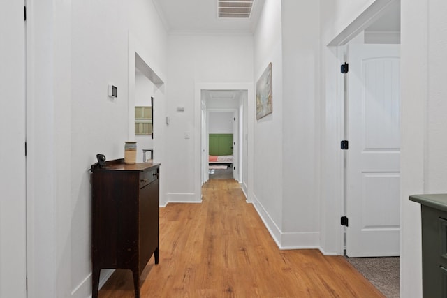 hallway with light hardwood / wood-style floors and crown molding