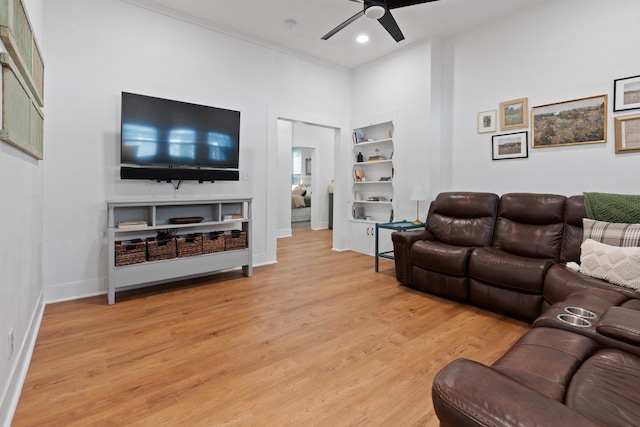 living room featuring ceiling fan, built in features, ornamental molding, and light wood-type flooring