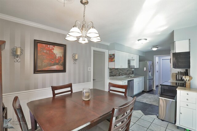 tiled dining area featuring crown molding, sink, and a chandelier