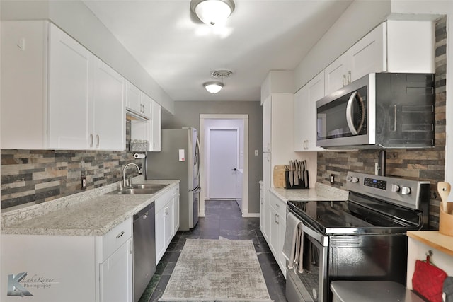 kitchen with decorative backsplash, appliances with stainless steel finishes, light stone counters, sink, and white cabinets