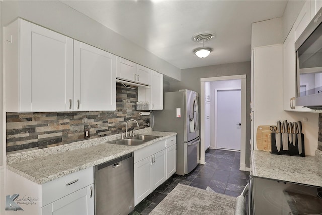 kitchen featuring sink, stainless steel appliances, tasteful backsplash, light stone counters, and white cabinets