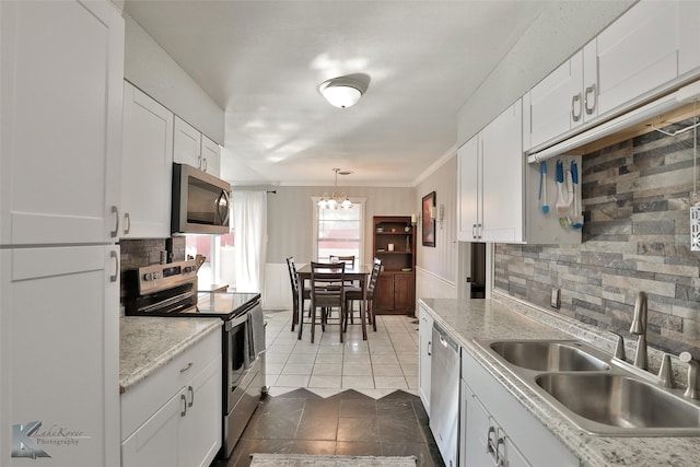 kitchen with pendant lighting, backsplash, white cabinets, sink, and stainless steel appliances