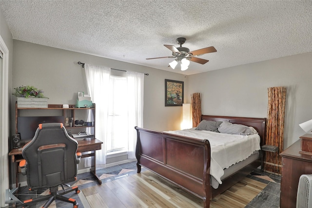 bedroom with a textured ceiling, ceiling fan, and light wood-type flooring