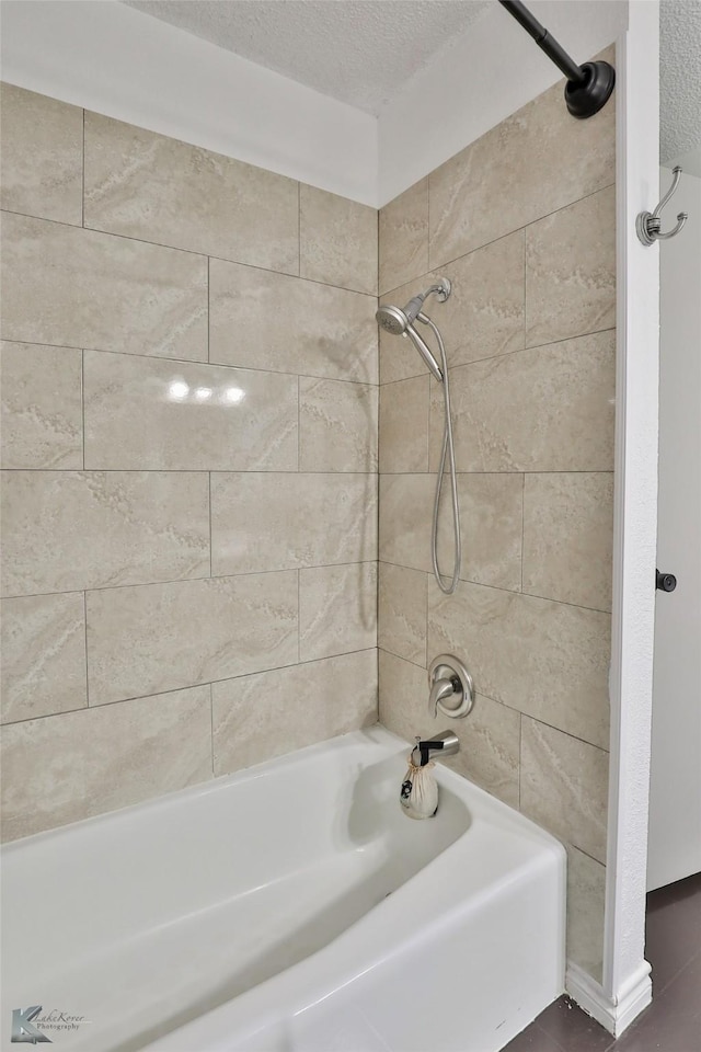 bathroom featuring tiled shower / bath combo and a textured ceiling